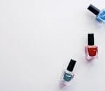 Three colorful nail polish bottles arranged creatively on a white backdrop, showcasing vibrant beauty products.