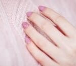 Close-up of a woman's hand with pink manicure resting on a soft knit sweater, showcasing elegance and fashion.
