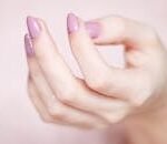 A close-up of a woman's hand showing a stylish pink and glittery manicure.